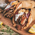 Greek gyros wrapped in pita breads on a wooden background