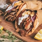 Greek gyros wrapped in pita breads on a wooden background