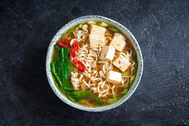 Japanese ramen soup with tofu on dark stone background. Miso soup with ramen noodles and tofu in ceramic bowl, asian traditional food.