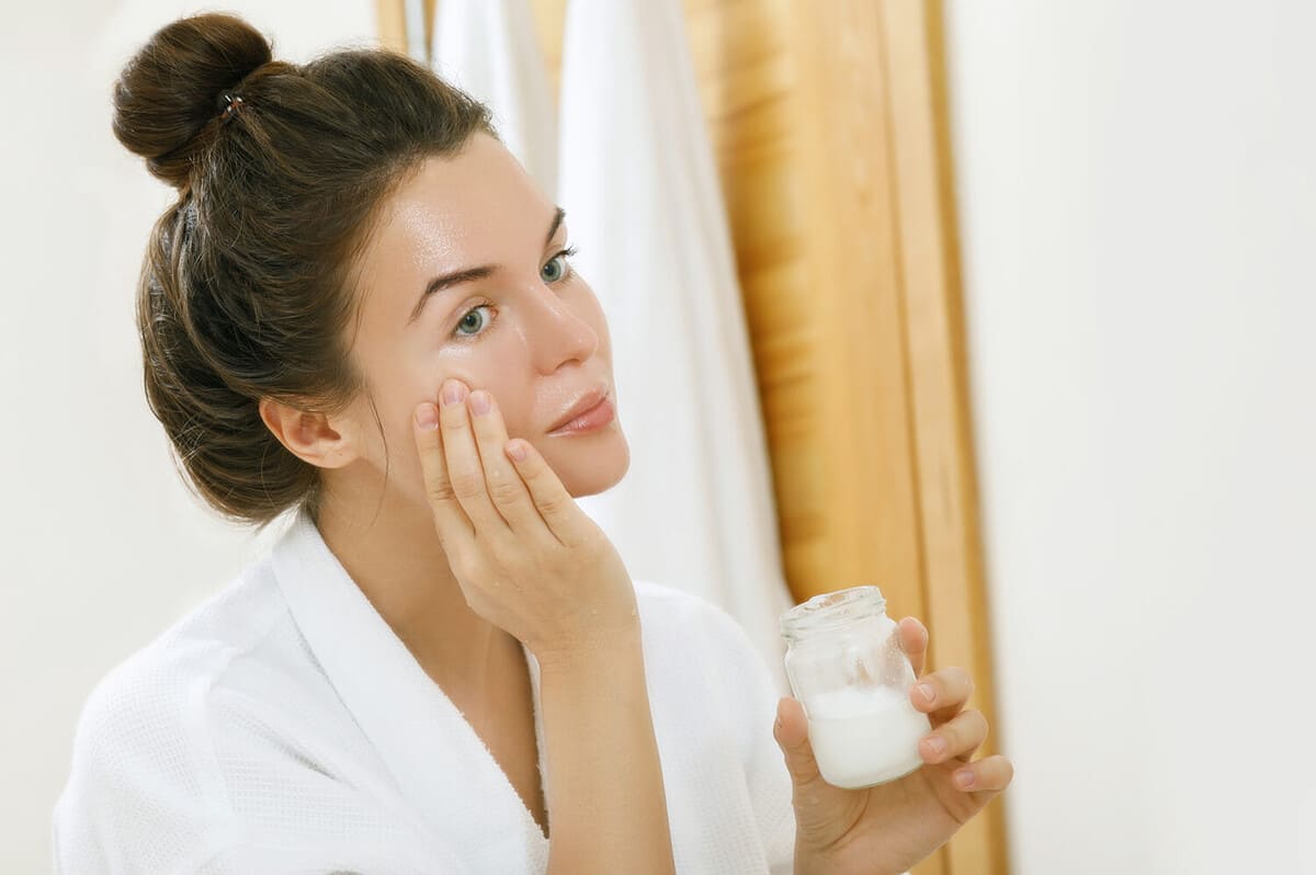 Woman is moisturizing her skin with a coconut oil