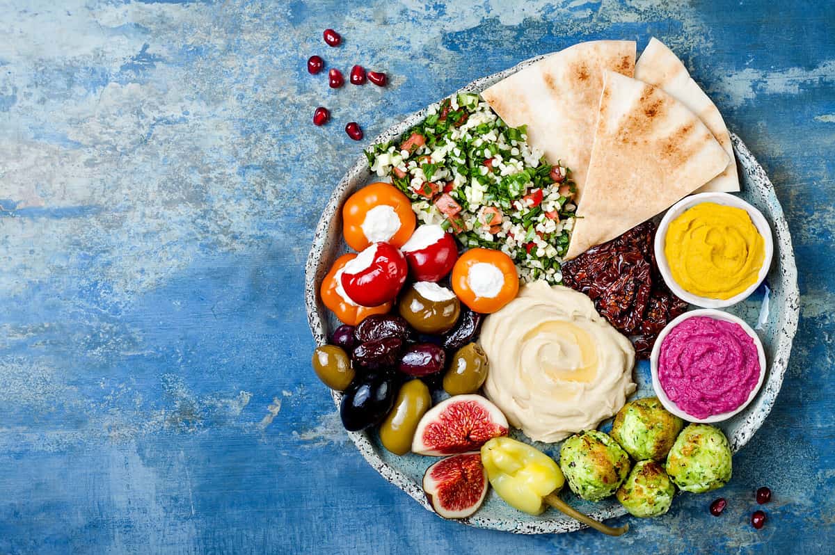 Middle Eastern meze platter with green falafel, pita, sun dried tomatoes, pumpkin and beet hummus.Mediterranean appetizer party idea