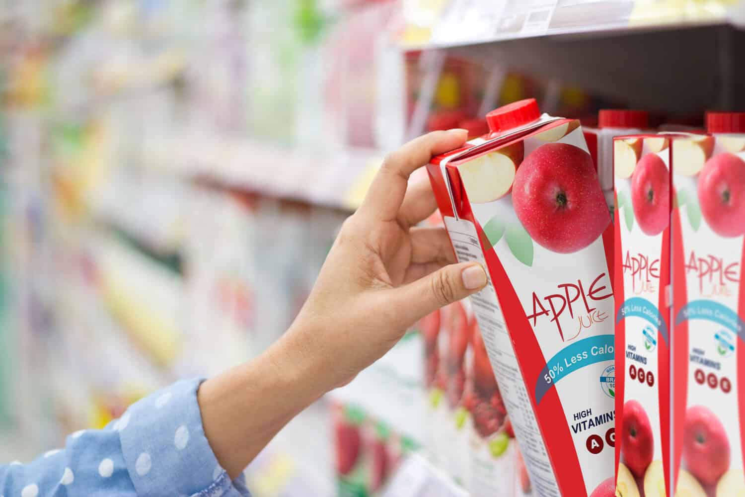 Woman hand choosing to buy apple juice on shelves in supermarket