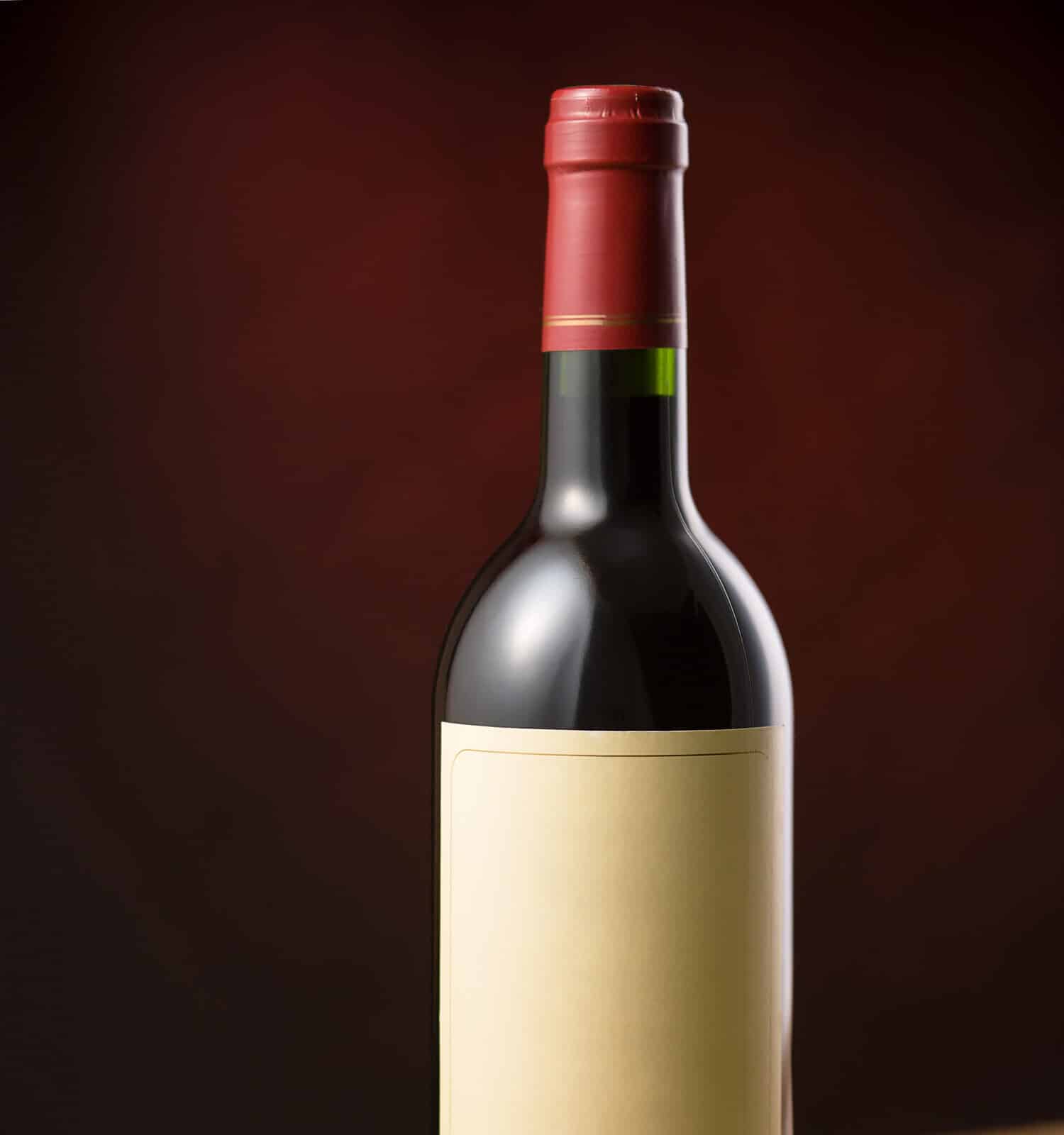 Red wine bottle on wooden table over dark red background