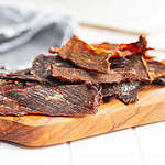 Beef jerky meat Dried sliced meat on wooden cutting board.