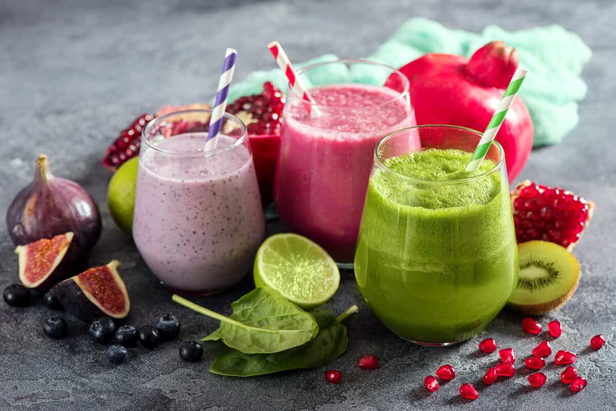 Colorful smoothie, healthy detox vitamin diet or vegan food concept, fresh vitamins, breakfast drink with spinach, pomegranate, figs and blueberries