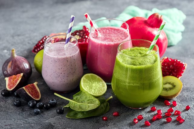 Colorful smoothie, healthy detox vitamin diet or vegan food concept, fresh vitamins, breakfast drink with spinach, pomegranate, figs and blueberries