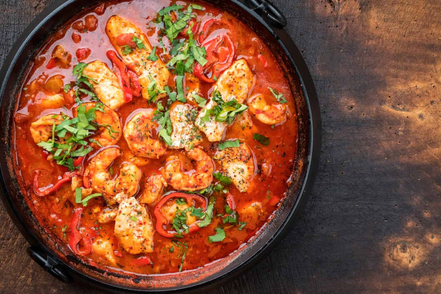 Traditional Creole cajun court bouillon with fish and seafood gumbo chowder stew as top view in a pot with copy space right