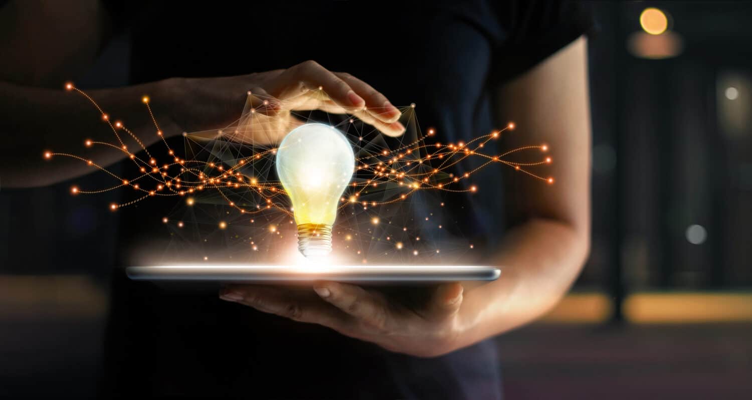 Abstract. Innovation. Hands holding tablet with light bulb future technologies and network connection on virtual interface background, innovative technology in science and communication concept