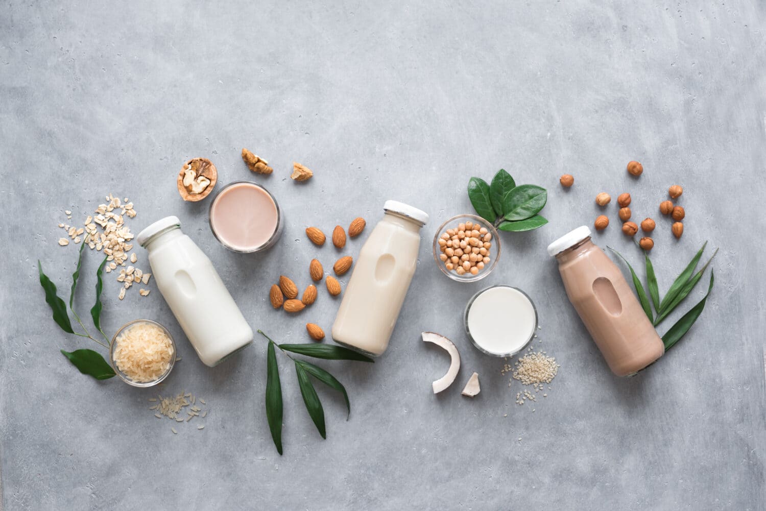 Various vegan plant based milk and ingredients, top view, copy space. Dairy free milk substitute drink, healthy eating.