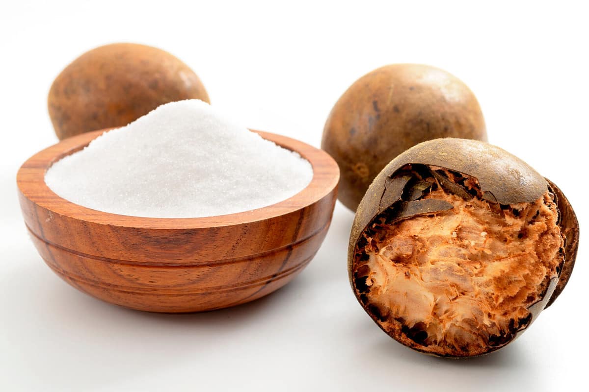 Low calorie alternative to sugar and natural remedy for inflammatory disease and arthritis conceptual idea with Luo Han Guo or Monk fruit and bowl of powder sweetener isolated on white background