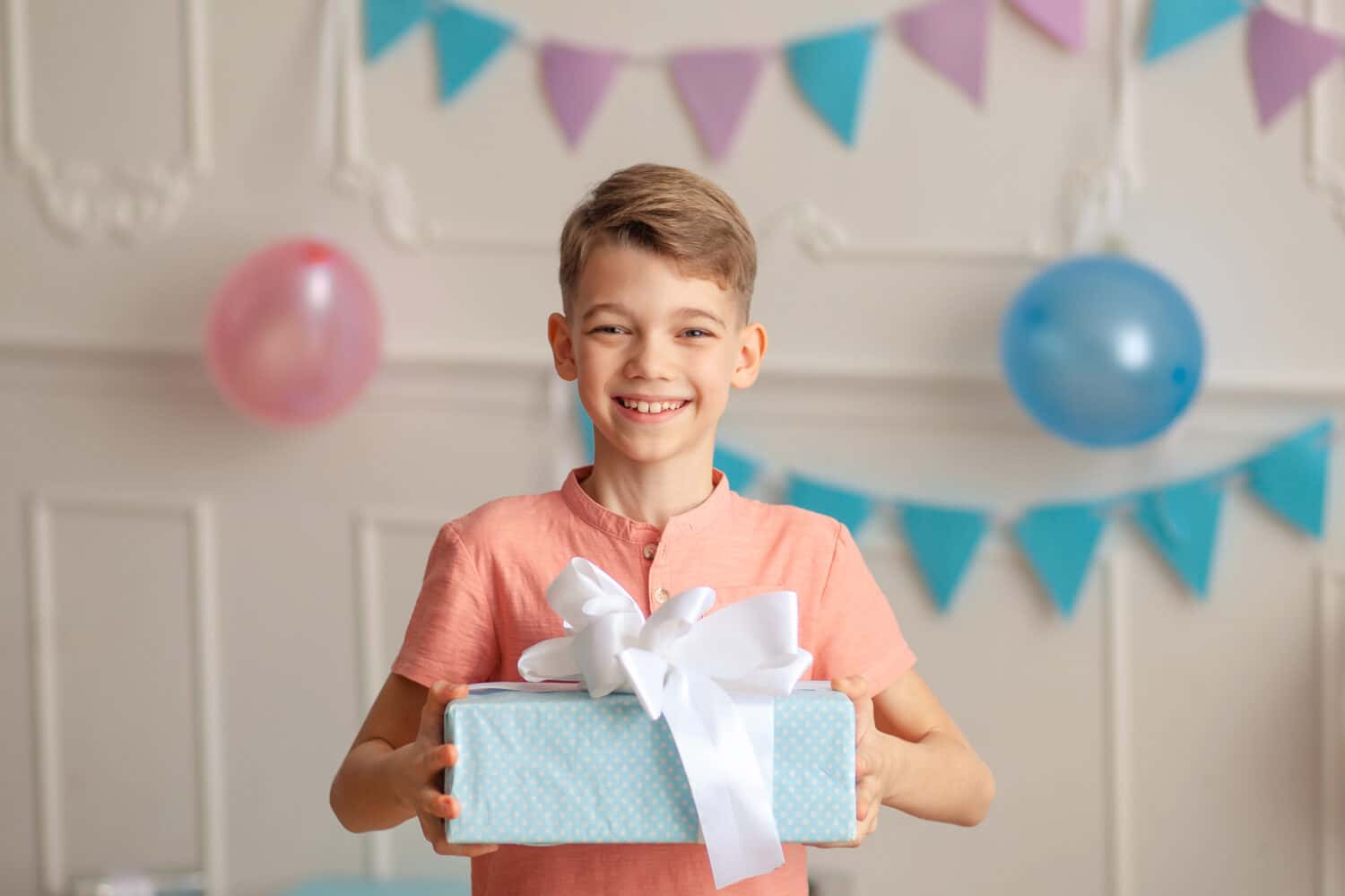 Happy Birthday Portrait of a happy cute boy of 8-9 years old in a festive decor with confetti and gifts.