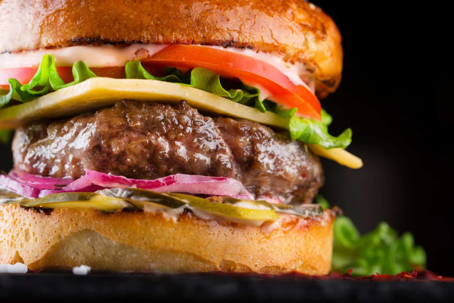 Close-up Tasty burger with beef, tomato, pickled, onion, lettuce and sauce