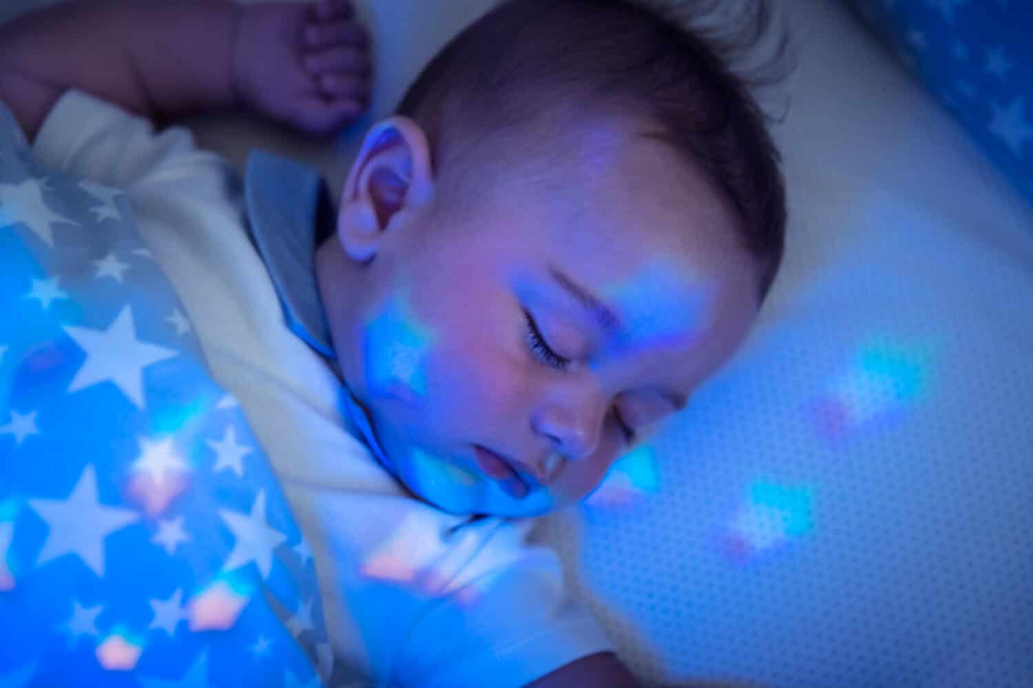 Portrait of nice sleeping baby boy, pretty child resting in his bed, star-shaped night light, healthy and peaceful childhood, new life concept
