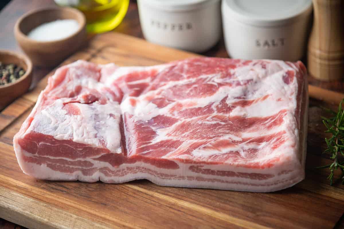 fresh pork belly block on wooden board