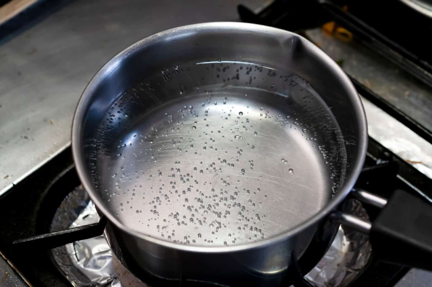 Boiling water in stainless pan in kitchen