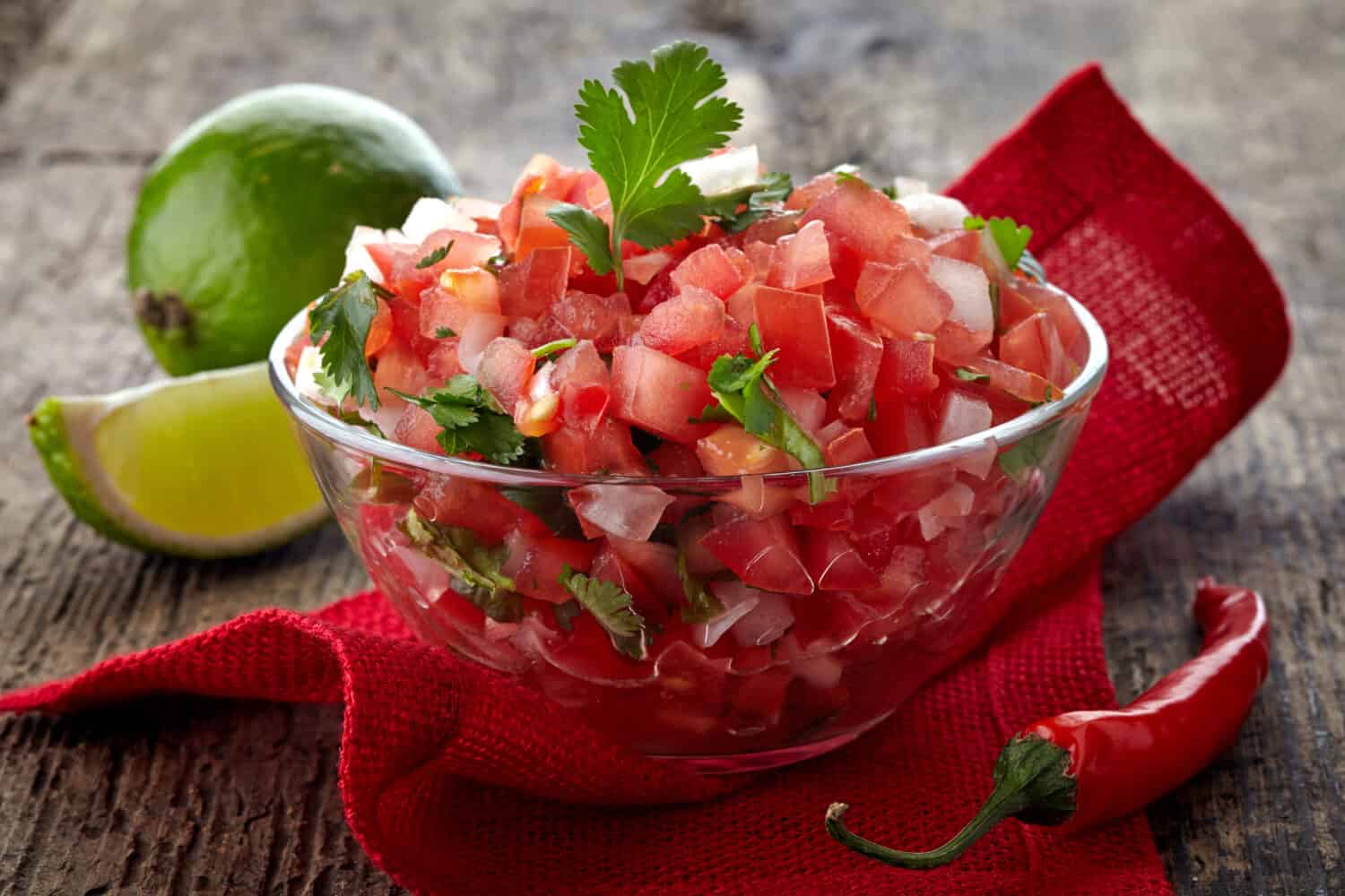 Bowl of fresh salsa dip on wooden background