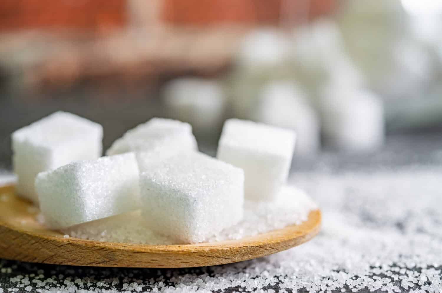 sugar cubes on black backround. Sugar is unhealthy nutrition and leads to obesity, diabetes, dental care