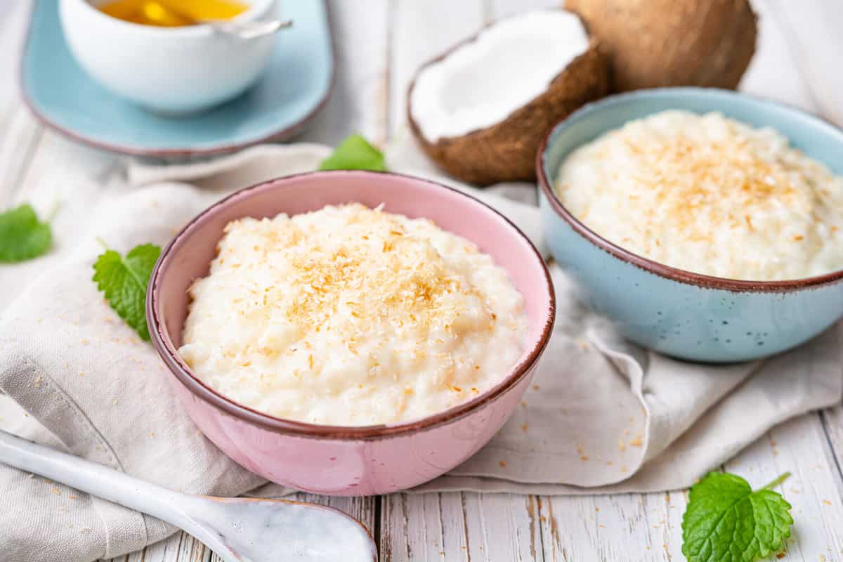 Sweet and creamy coconut rice pudding with honey, topped with grated and toasted coconut in a ceramic bowl