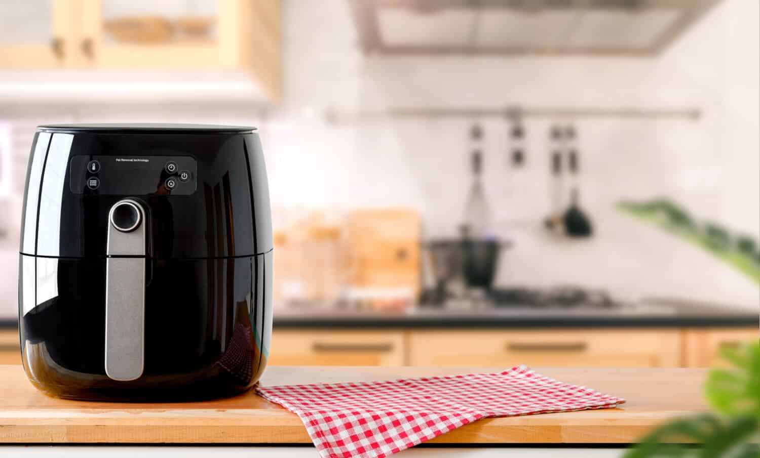 An electric Air Fryer on table with blurred kitchen background. Lifestyle of new normal cooking.