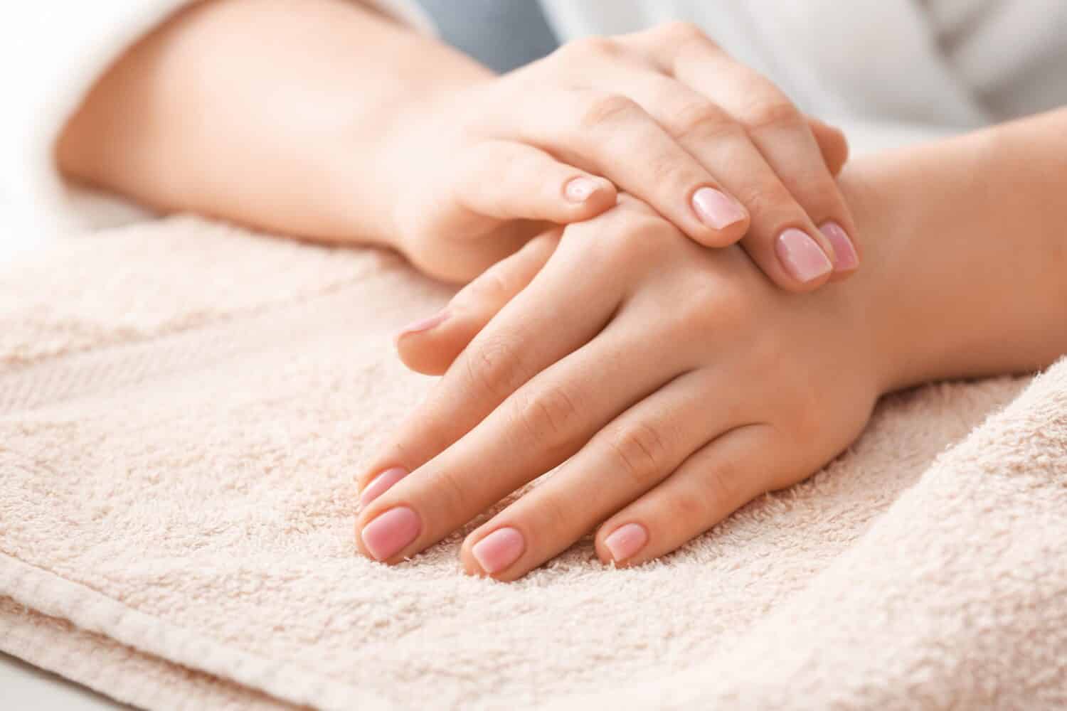 Beautiful female hands and towel on light background