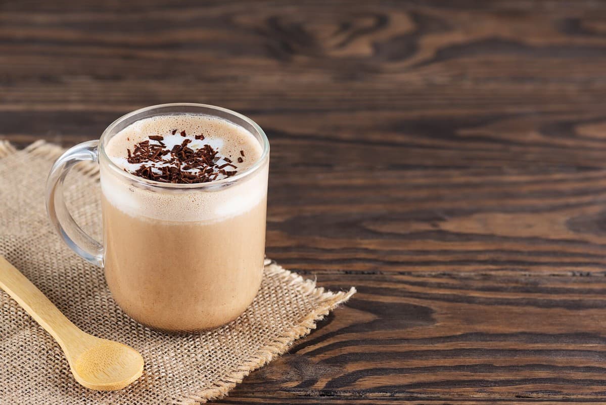 Mocha of coffee with chocolate, hazelnuts and coconut milk in a glass cup. Sugar, gluten and lactose free. Horizontal orientation, copy space.