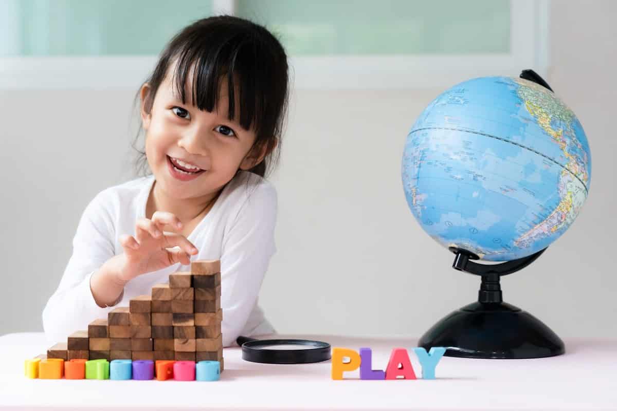 Adorable 4 years old asian little girl is learning the bilingual globe model contain english and thai language, concept of save the world and learn through play activity for kid education at home.
