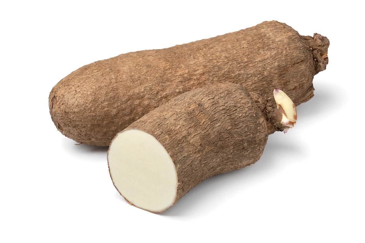 Whole and halved raw African yam isolated on white background
