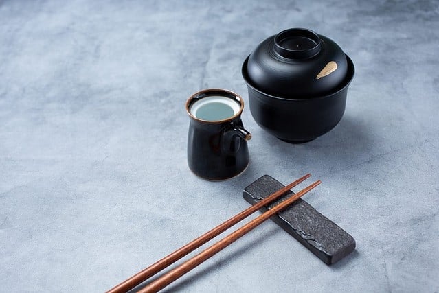 A view of a Japanese restaurant place setting, featuring chopsticks and soy sauce dishware.