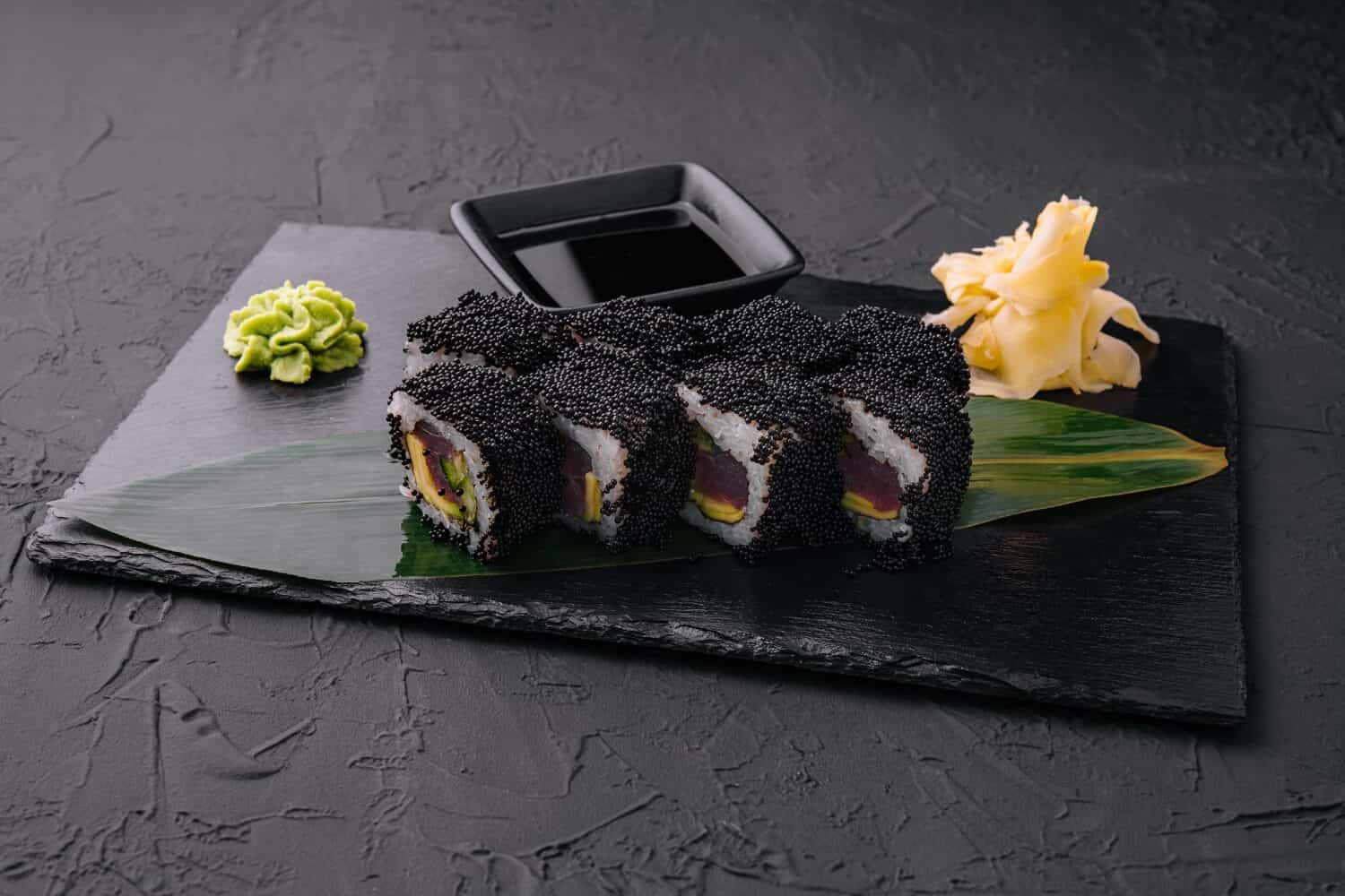 california rolls covered black tobiko on a black board