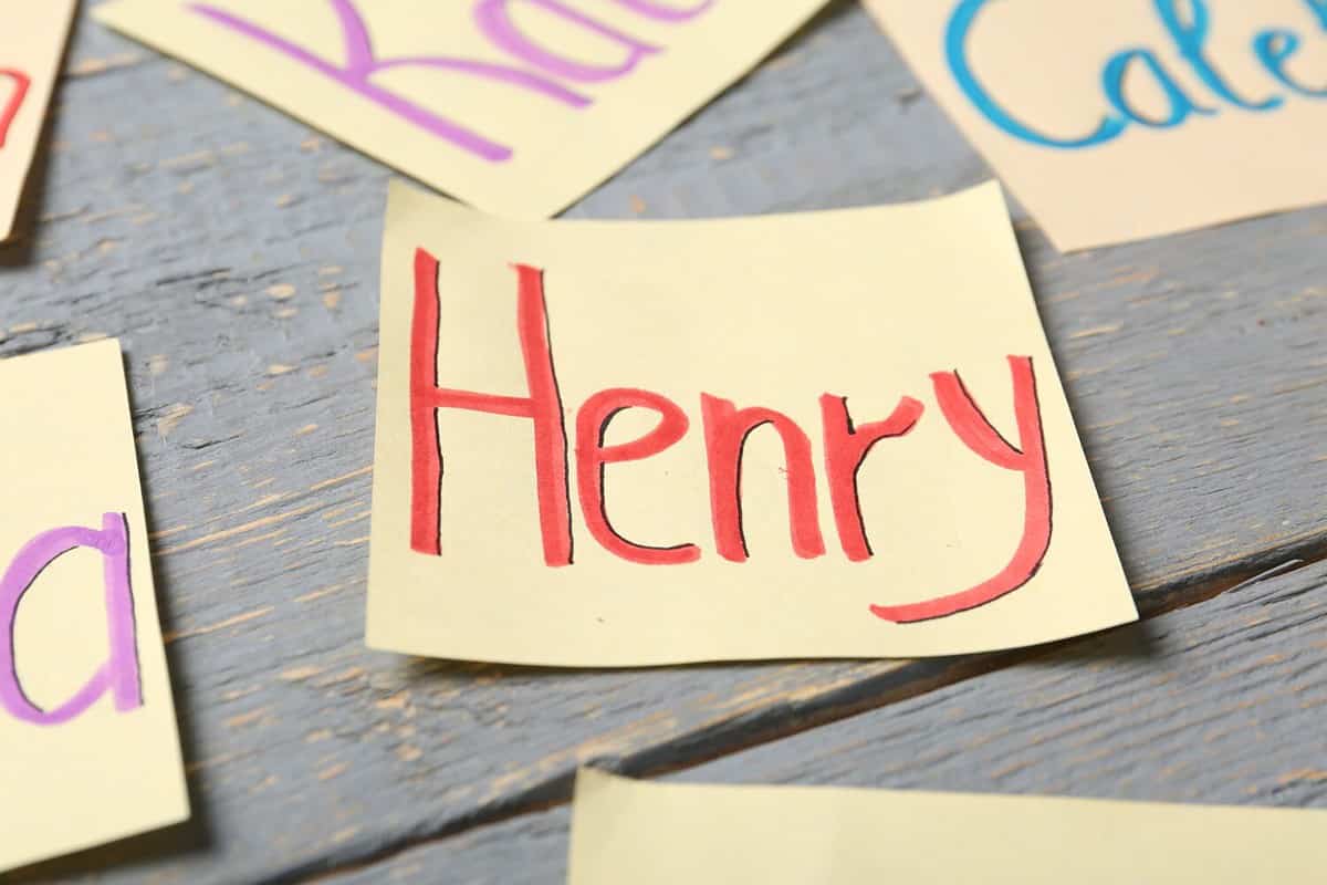 Paper sheet with baby name Henry on grey wooden table, closeup