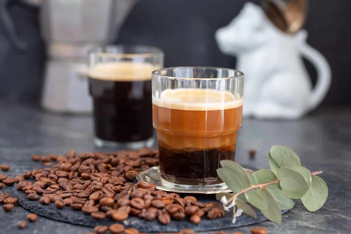 Espresso macchiato on dark table. Espresso macchiato in ripple glas. Natural light, selective focus.