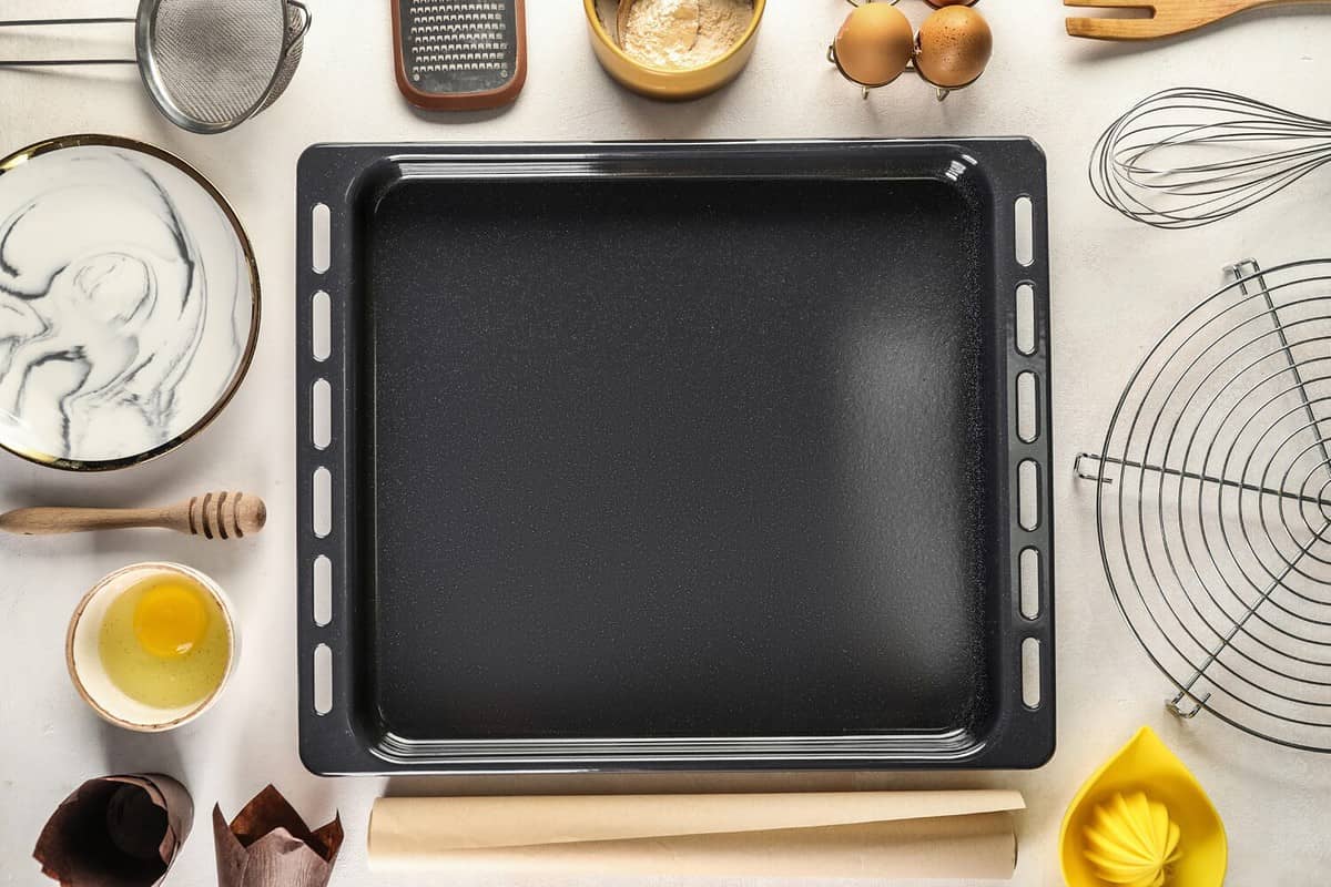 Baking tray with ingredients and utensils on white background