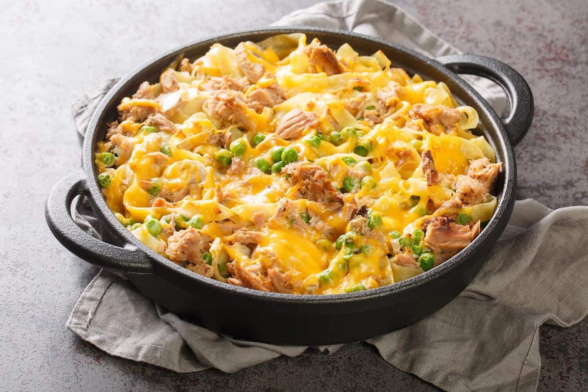 Homemade Cheesy Tuna Casserole with Peas and Egg Noodles closeup on the pan on the table. Horizontal