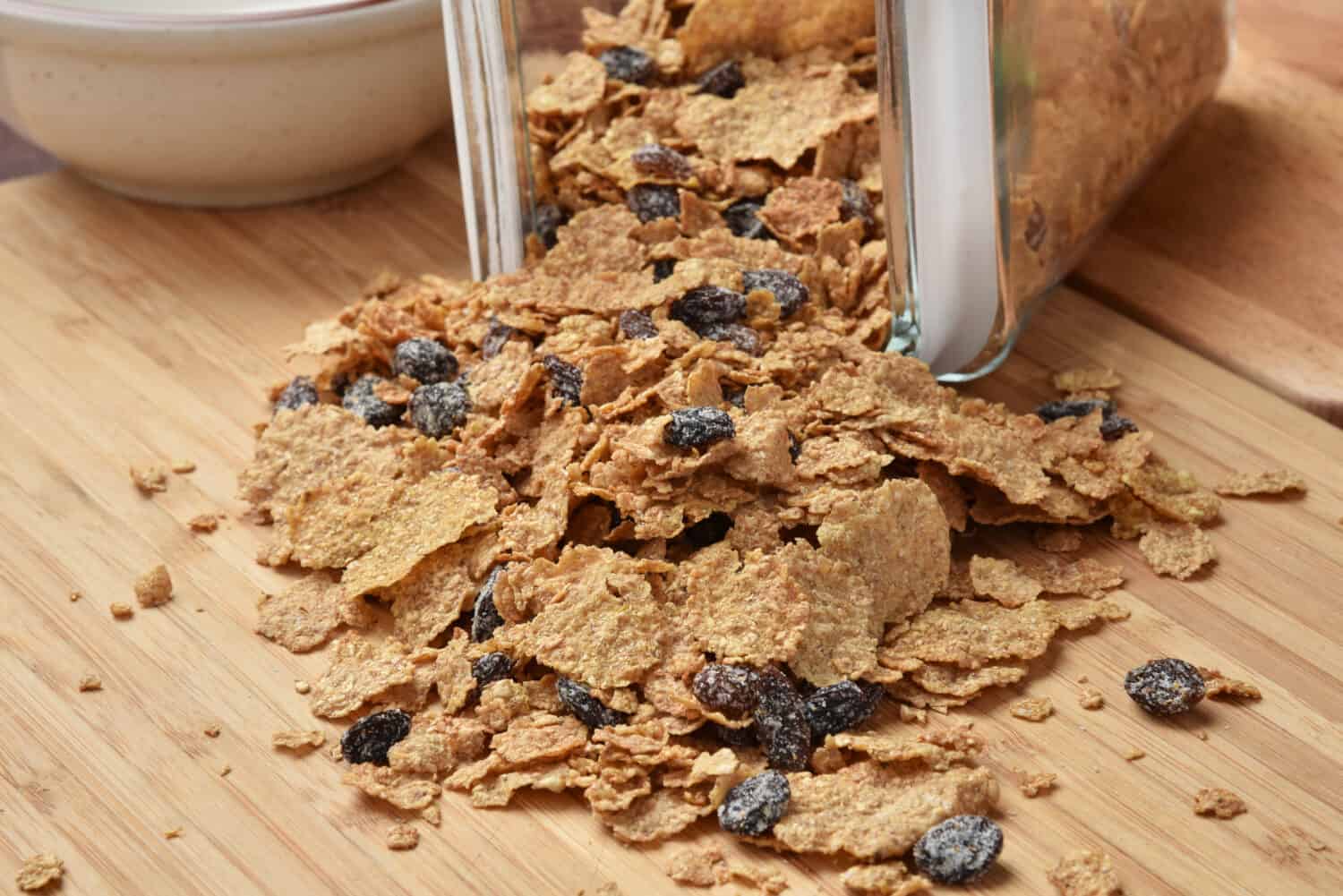 Bran and raisin cereal spilling out of a glass canister