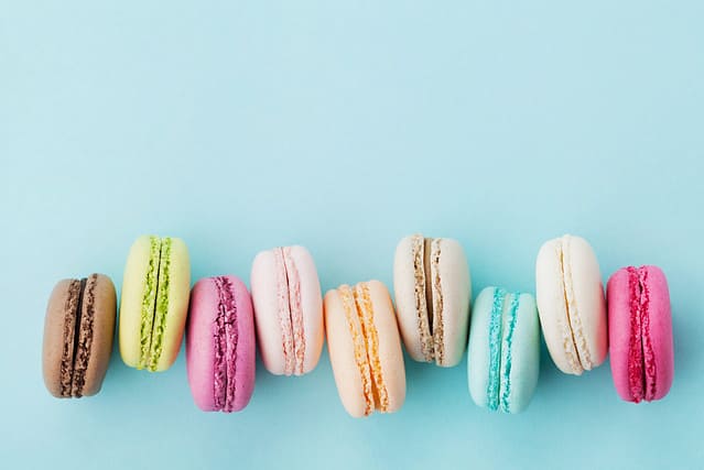 Cake macaron or macaroon on turquoise background from above, colorful almond cookies, pastel colors, vintage card, top view