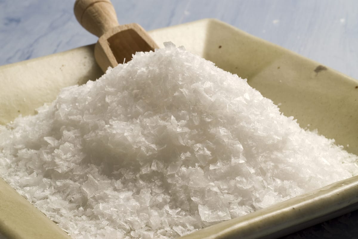 Maldon sea salt in a japanese ceramic plate. Blue background.Selective focus.