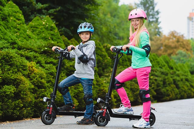 Happy kids standing on electric scooter outdoor