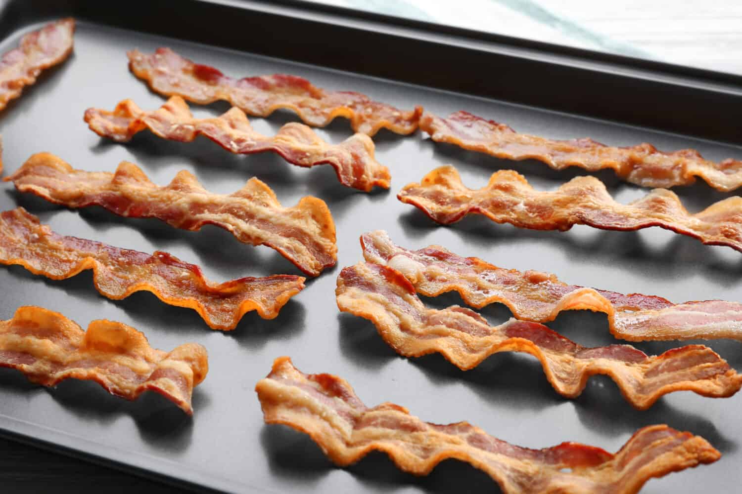 Baking tray with strips of fried bacon, closeup