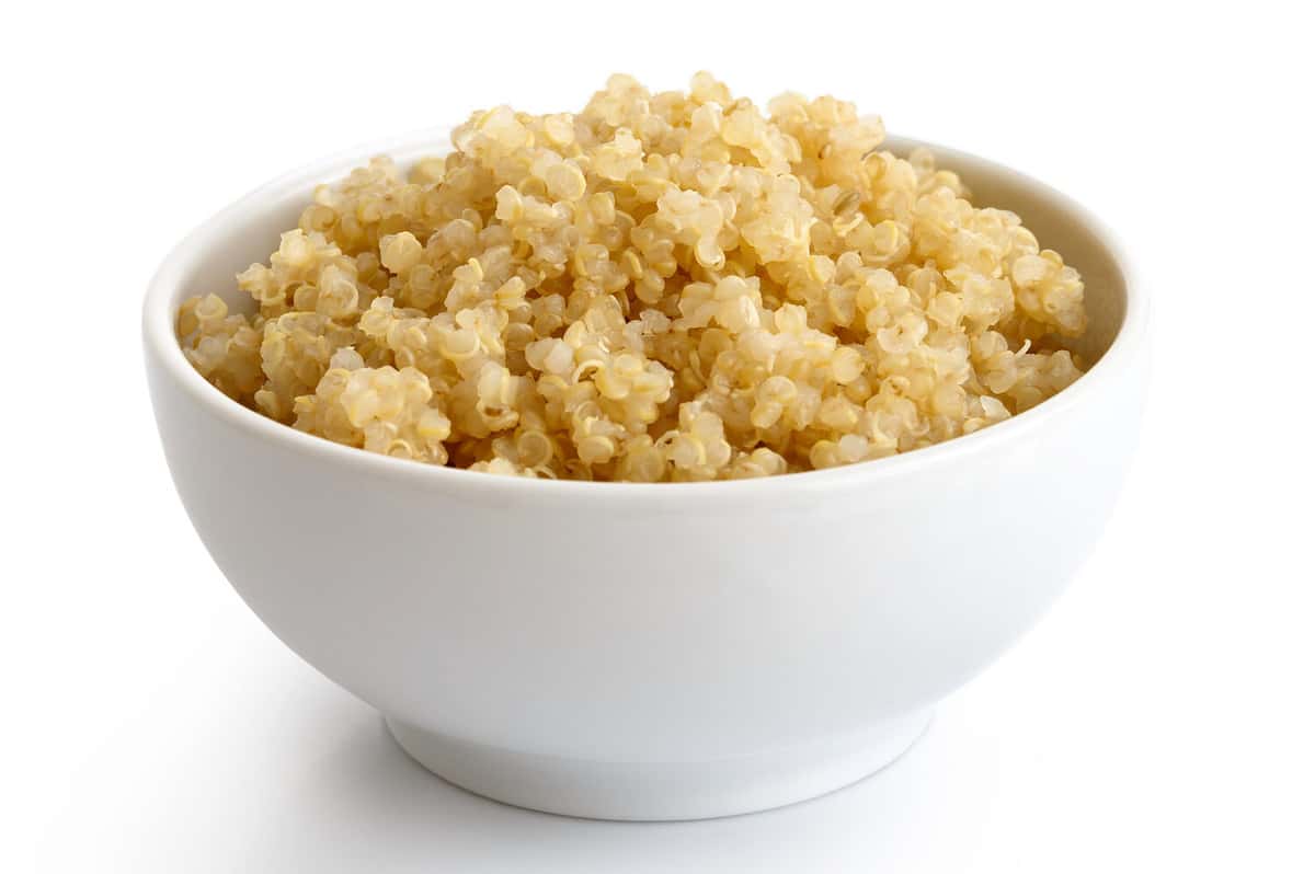 Cooked quinoa in white ceramic bowl isolated on white.