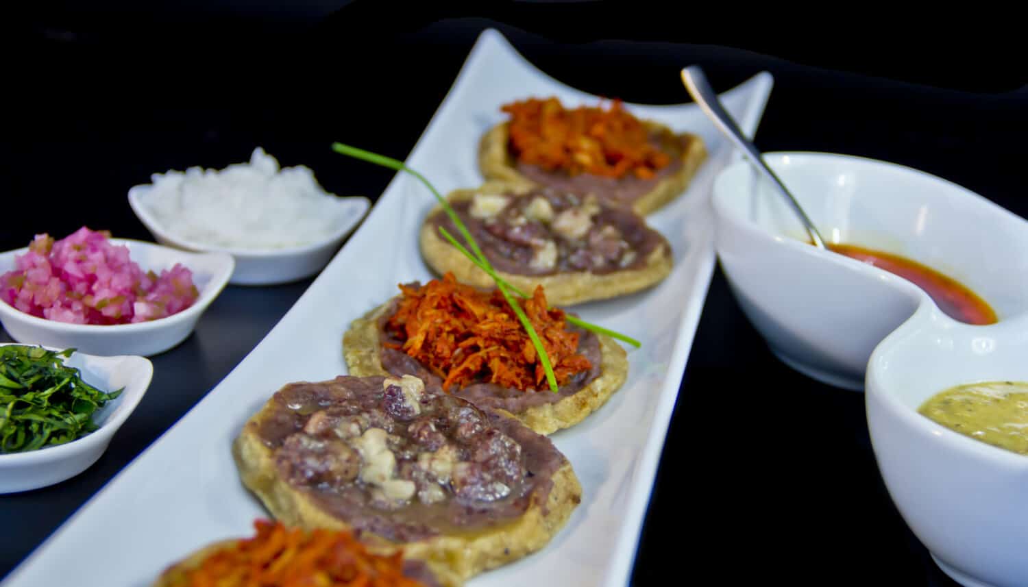 Corn tortilla snack with black beans and hot sauce