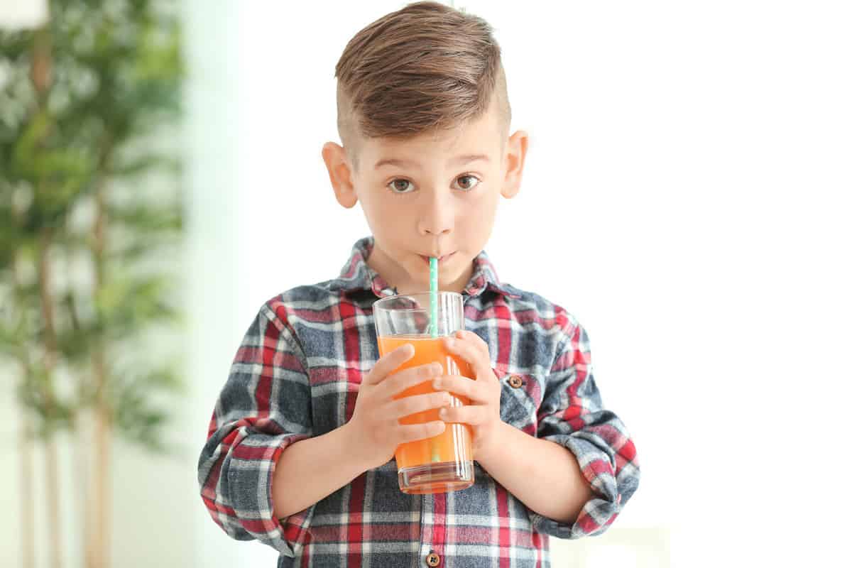 Cute little boy drinking juice at home