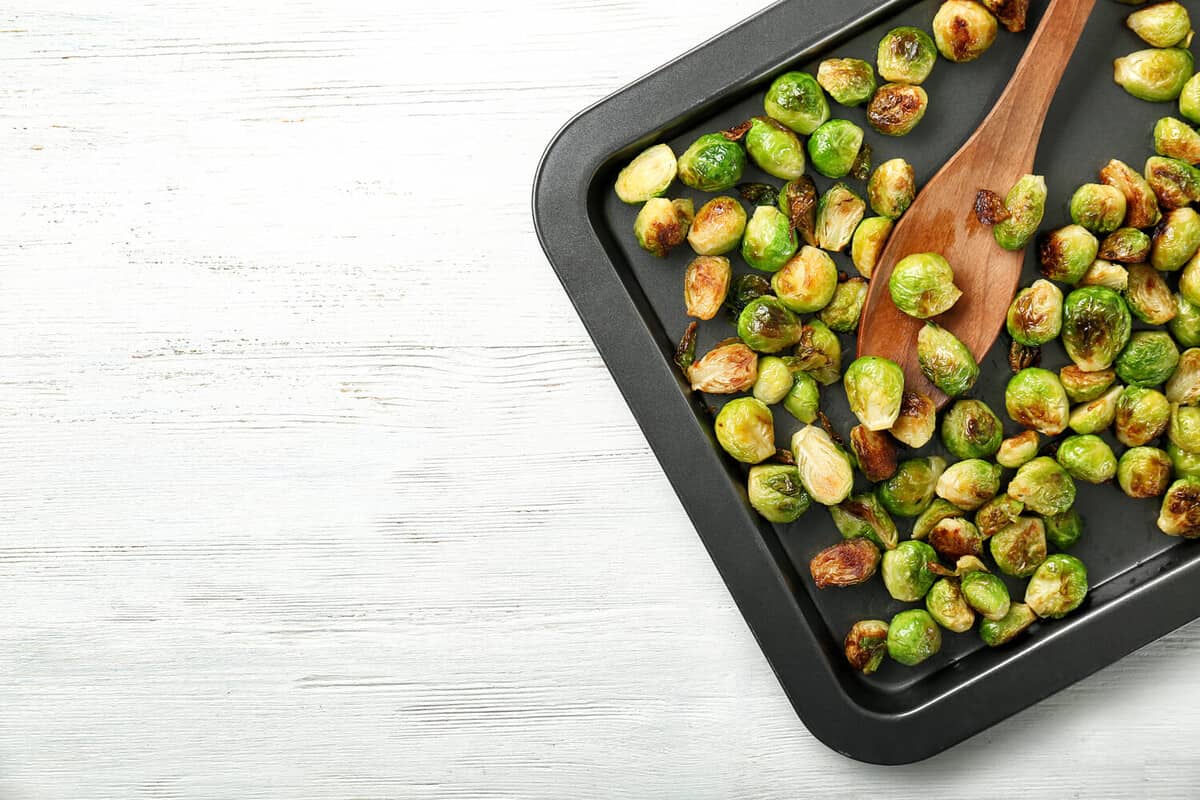 Baking sheet with roasted brussel sprouts on light background