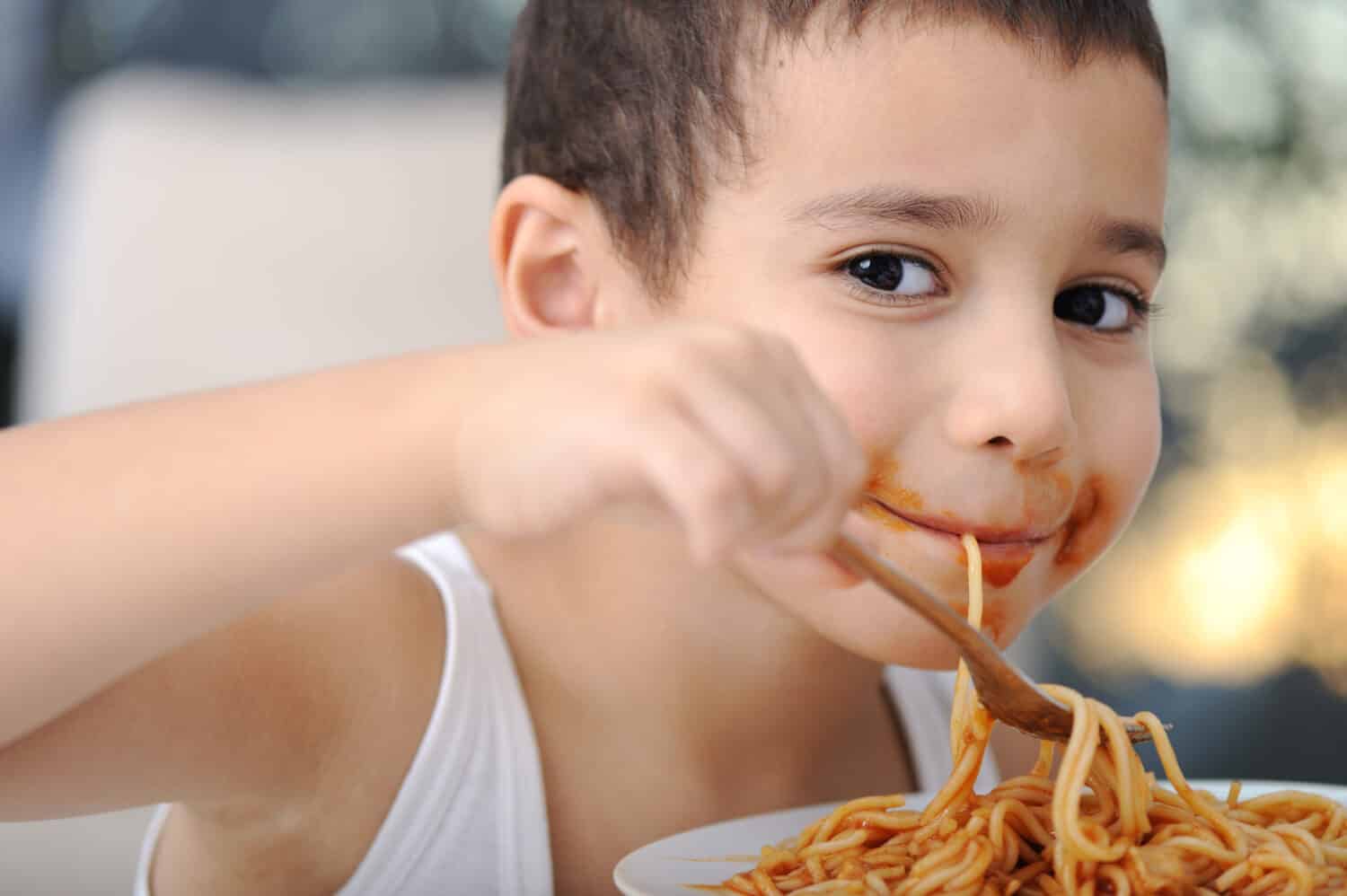 Tasty food, messy child eating spaghetti