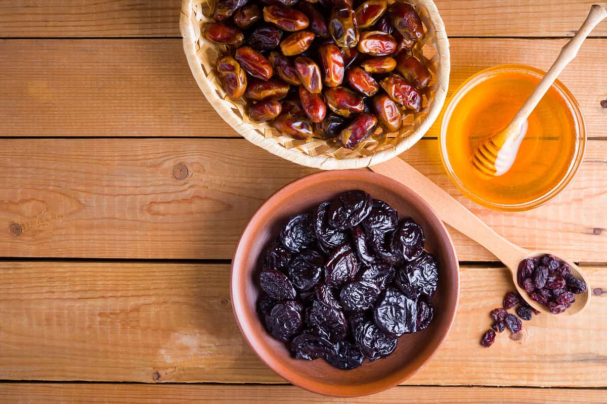 Dried dates, prunes and honey on wooden background. Holy month of Ramadan, concept. Righteous Muslim lifestyle. Starvation. Dried fruits: dates, prunes and raisins on wooden boards