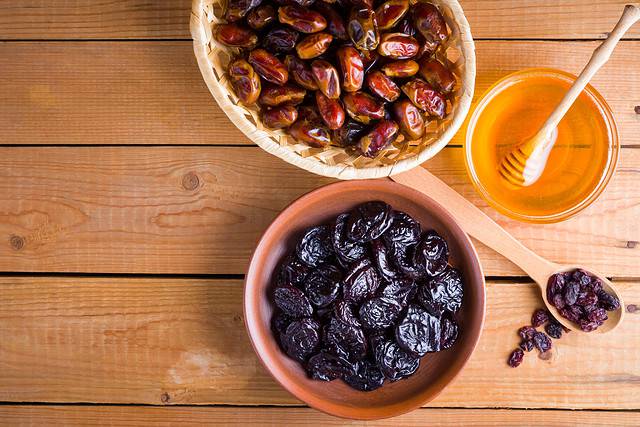Dried dates, prunes and honey on wooden background. Holy month of Ramadan, concept. Righteous Muslim lifestyle. Starvation. Dried fruits: dates, prunes and raisins on wooden boards