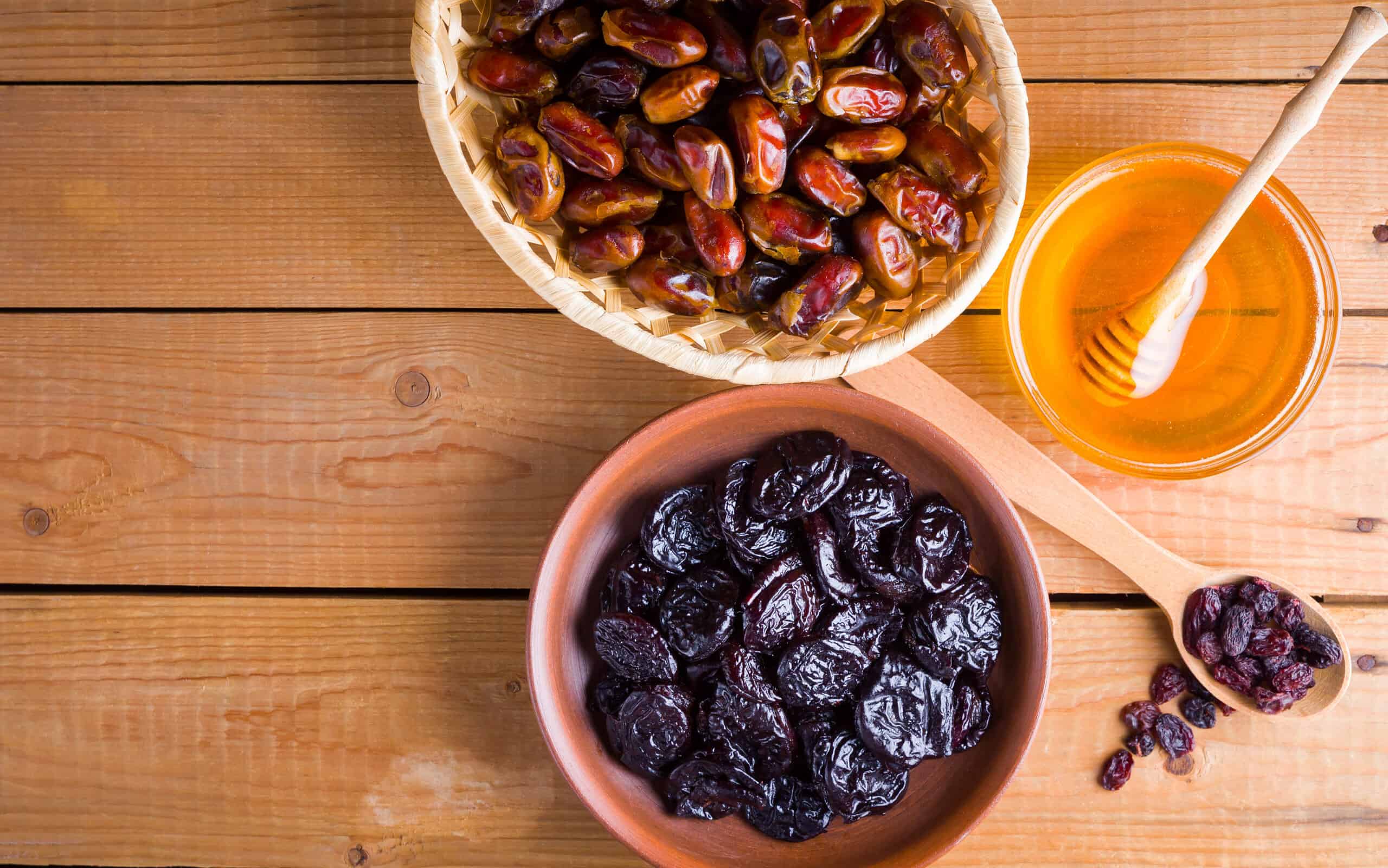 Dried dates, prunes and honey on wooden background. Holy month of Ramadan, concept. Righteous Muslim lifestyle. Starvation. Dried fruits: dates, prunes and raisins on wooden boards