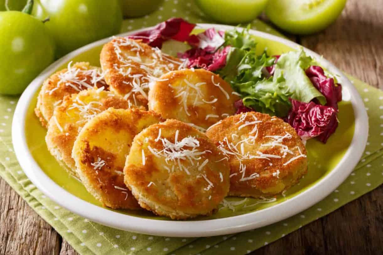 American food: fried green tomatoes with fresh salad close-up on a plate and ingredients on a table. horizontal