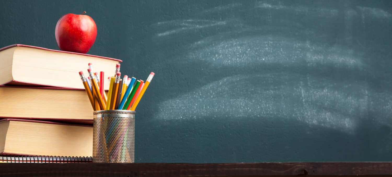 Back to school background with books and apple over blackboard