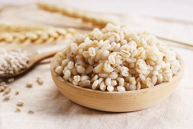 Cooked peeled barley grains in wooden plate