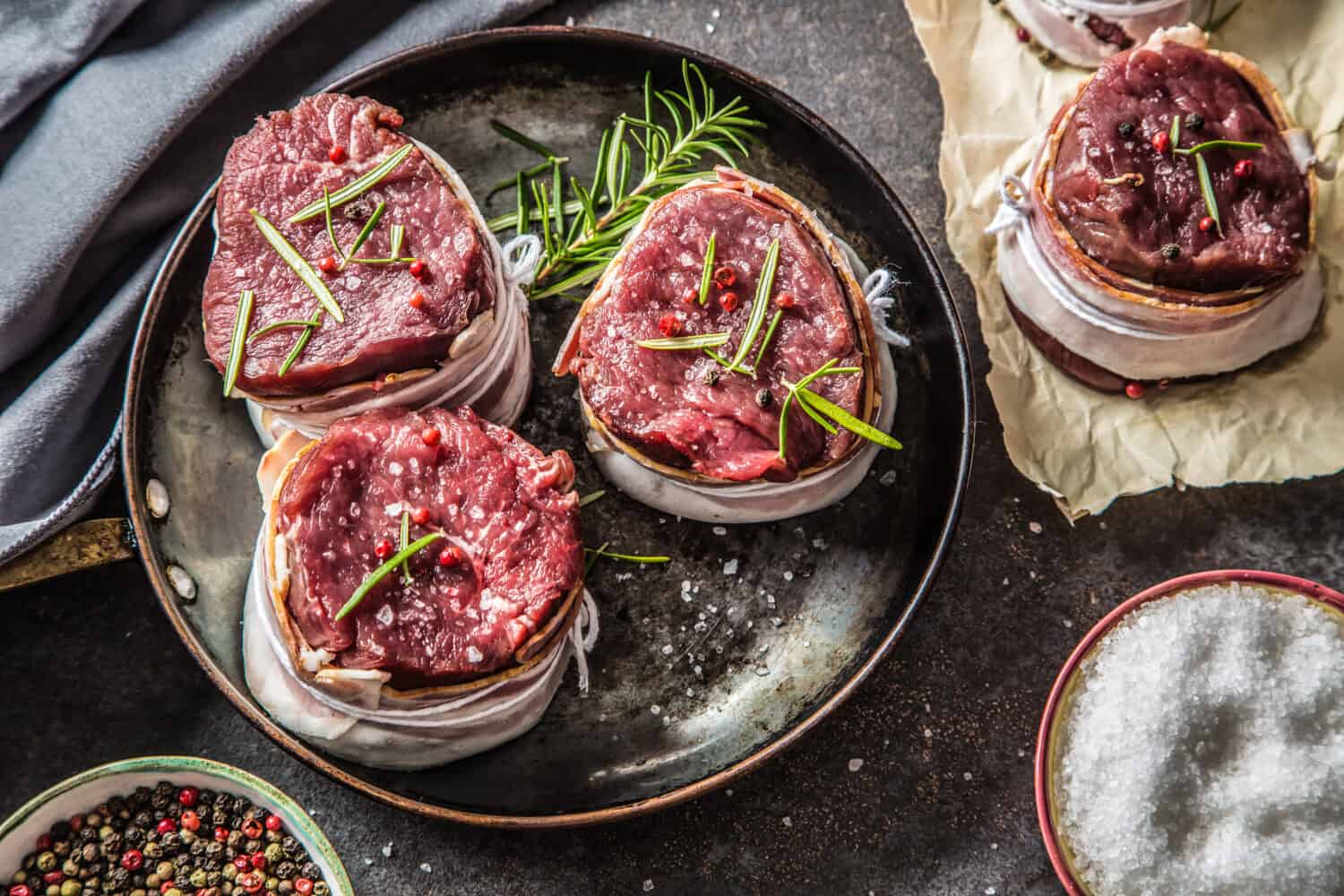 Beef tenderloin steaks wrapped in bacon stored into the pan.